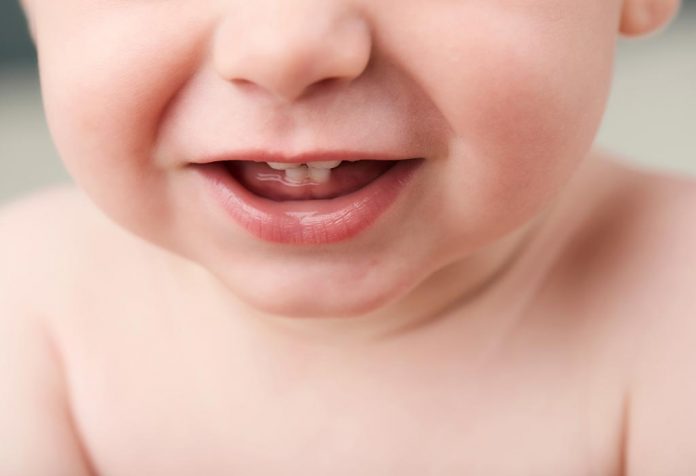 Um bebê mostrando os primeiros dentes.